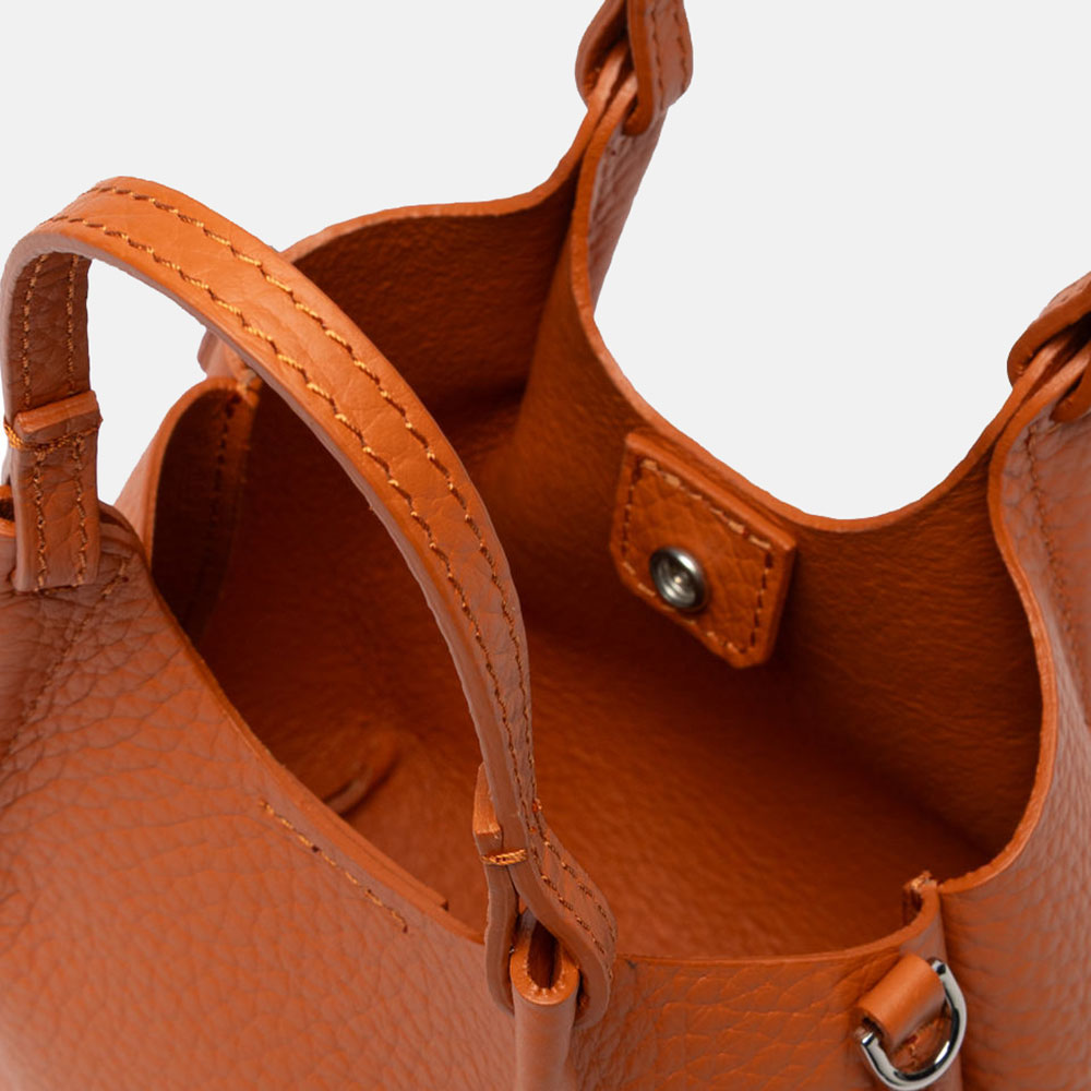 Close-up of an orange leather handbag with visible stitching and hardware.
