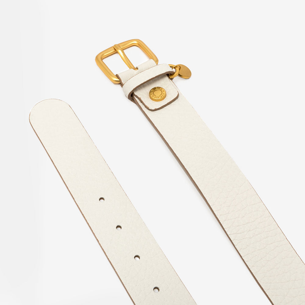 off white leather belt with gold buckle on a light grey background