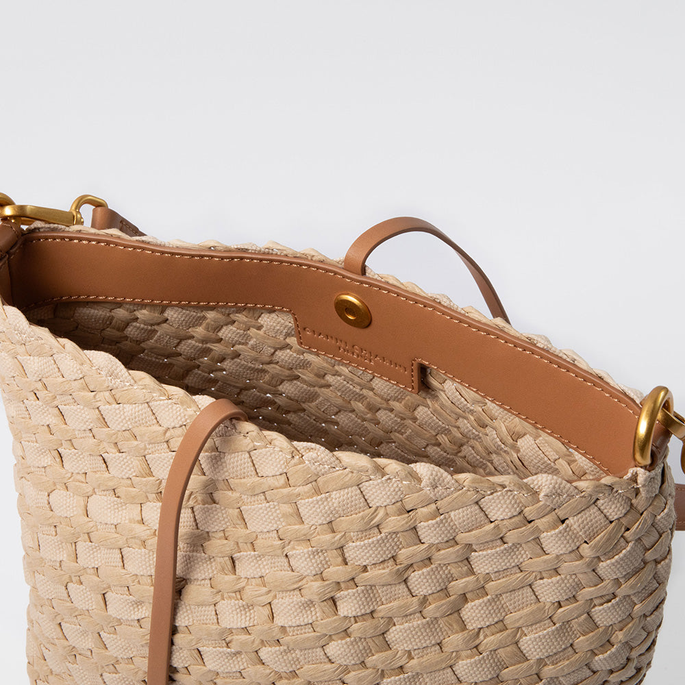 Woven straw & canvas handbag with brown leather accents on a light grey background