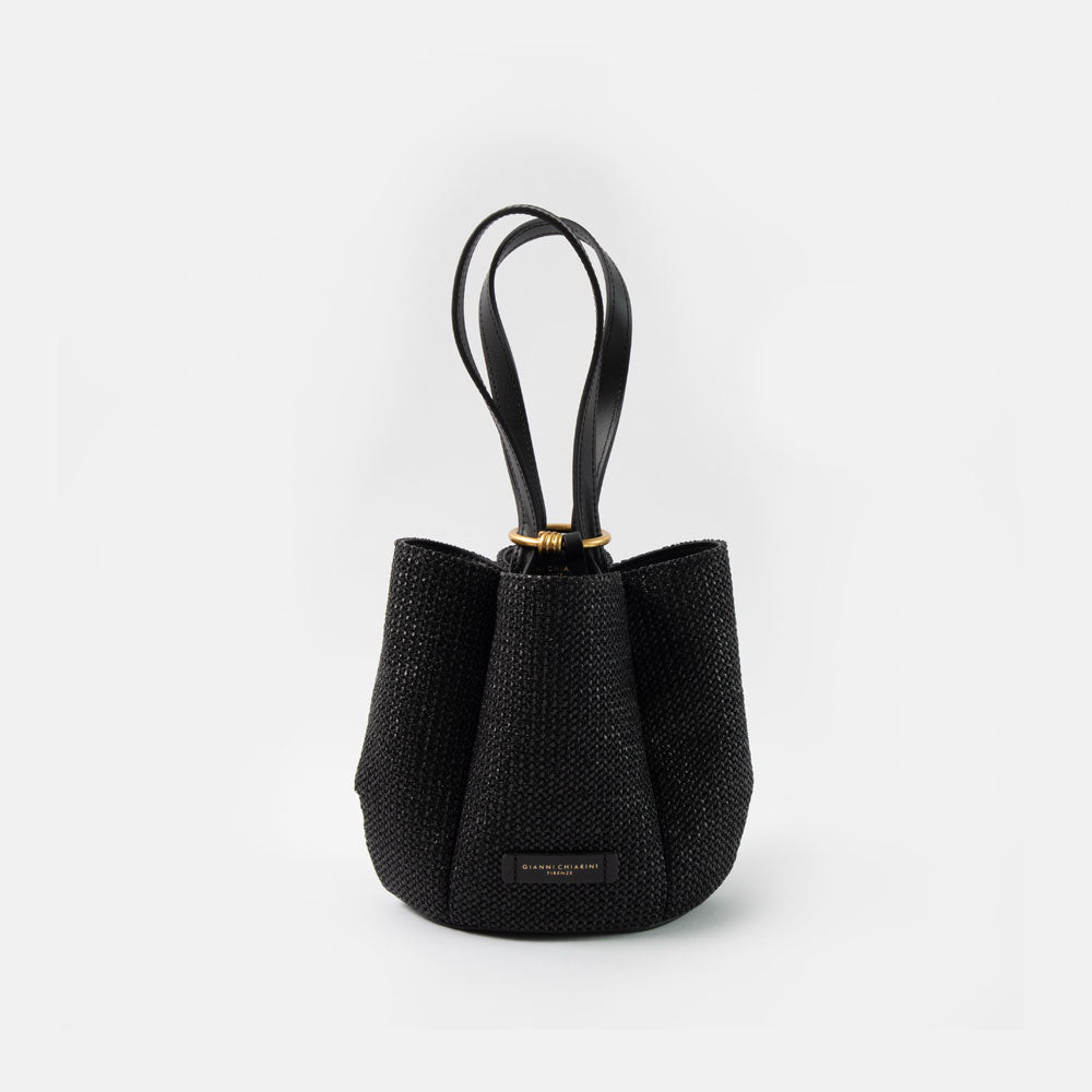 black woven straw bucket handbag with black leather shoulder straps and gold ring closure on a white background
