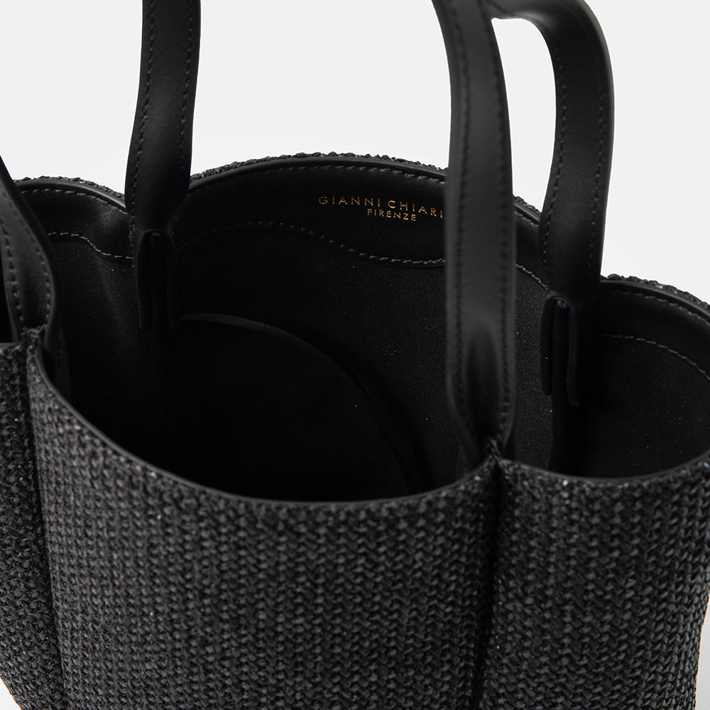 Close-up of a textured black woven straw handbag with visible brand name on a white background
