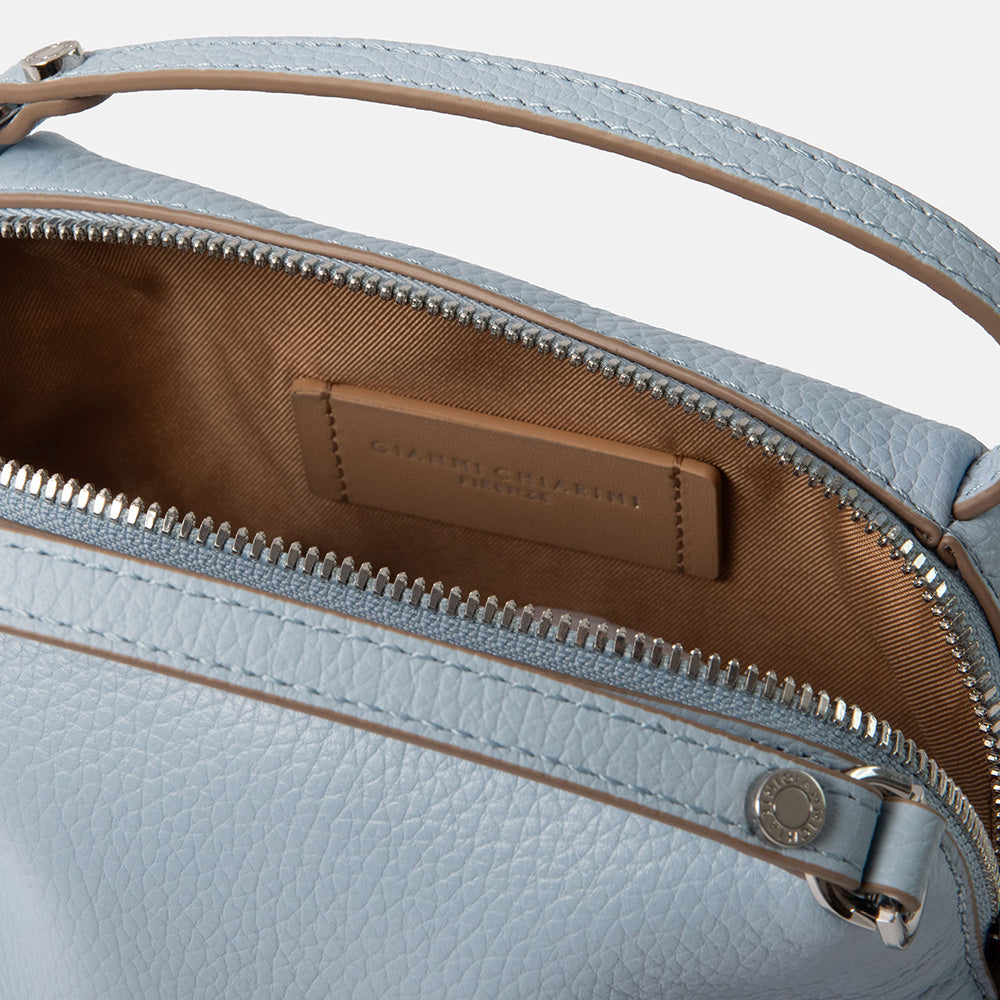 close up of a light blue leather handbag with canvas lining on a white background