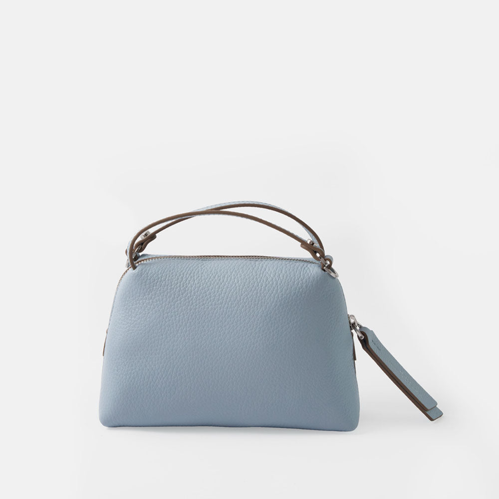 light blue leather small handbag with grab handles and removable crossbody strap on a white background