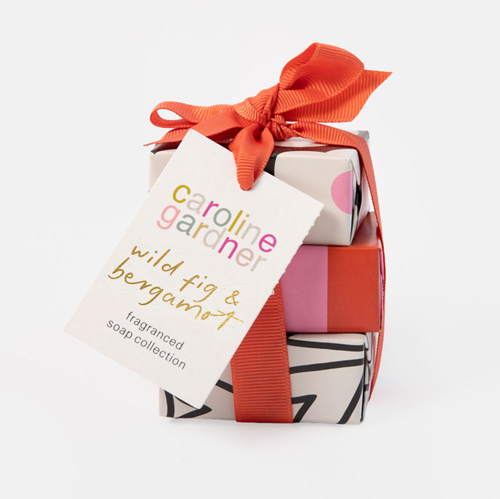 caroline gardner gift set of 3 soaps, individually wrapped in colourfully deisgned paper and tied up with an orange ribbon & bow