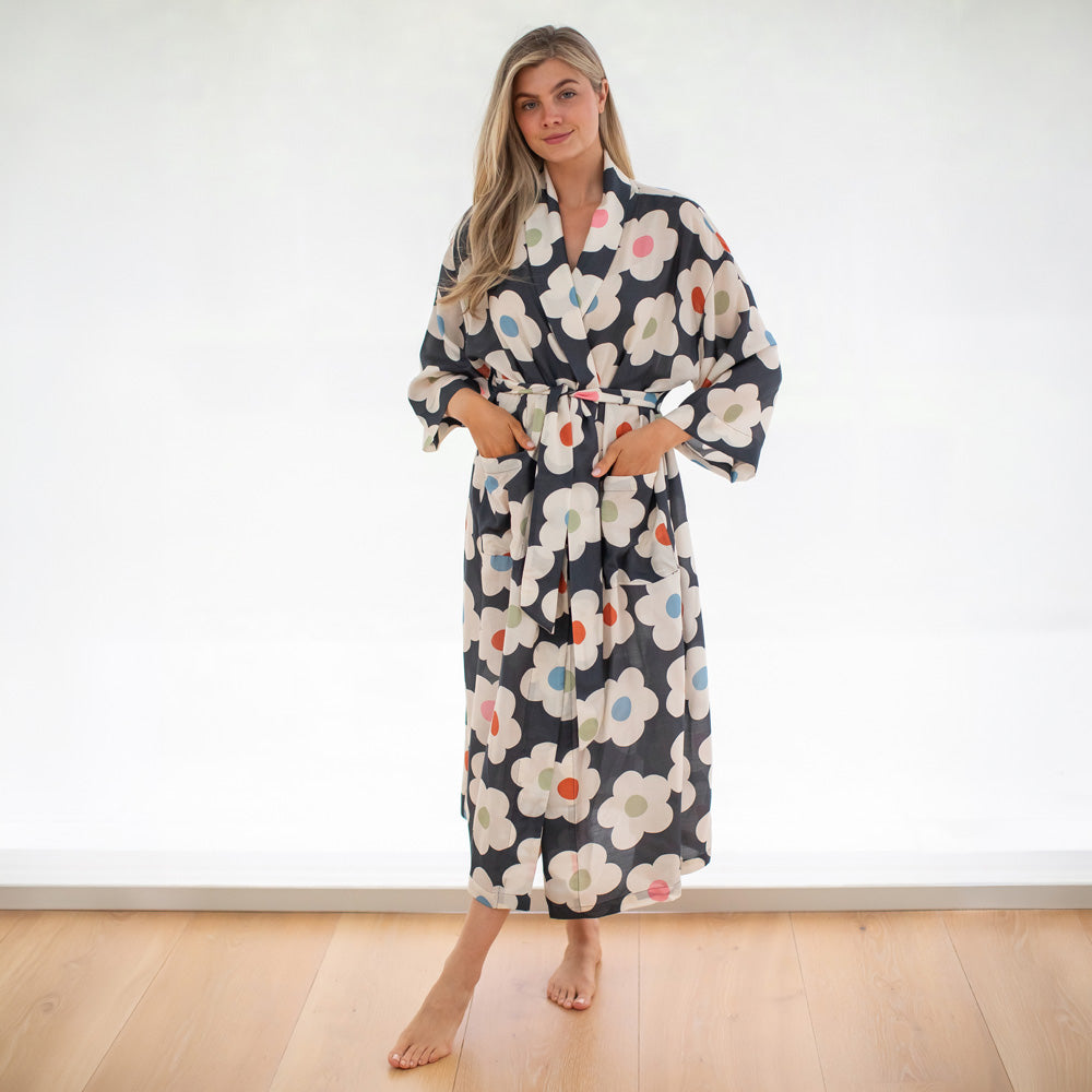 Woman wearing a floral robe standing in a minimalistic room.