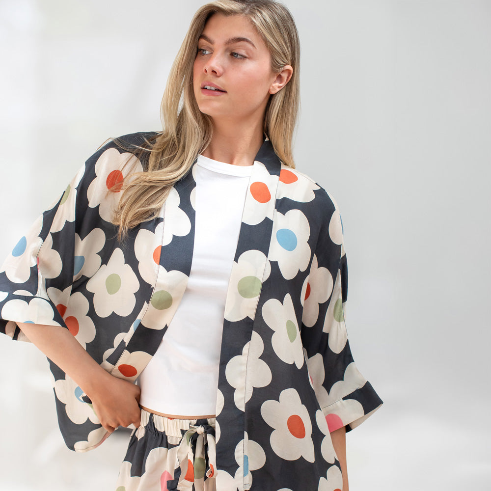 Woman wearing a floral patterned kimono-style garment against a white background