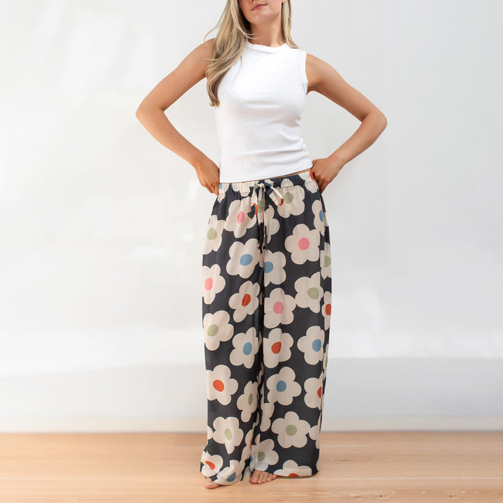 woman wearing floral palazzo pants with a white top in a minimal room