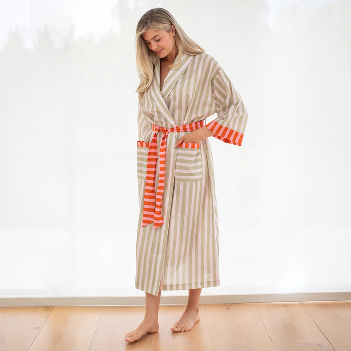 Woman wearing a striped robe with a red waistband in a minimal indoor setting