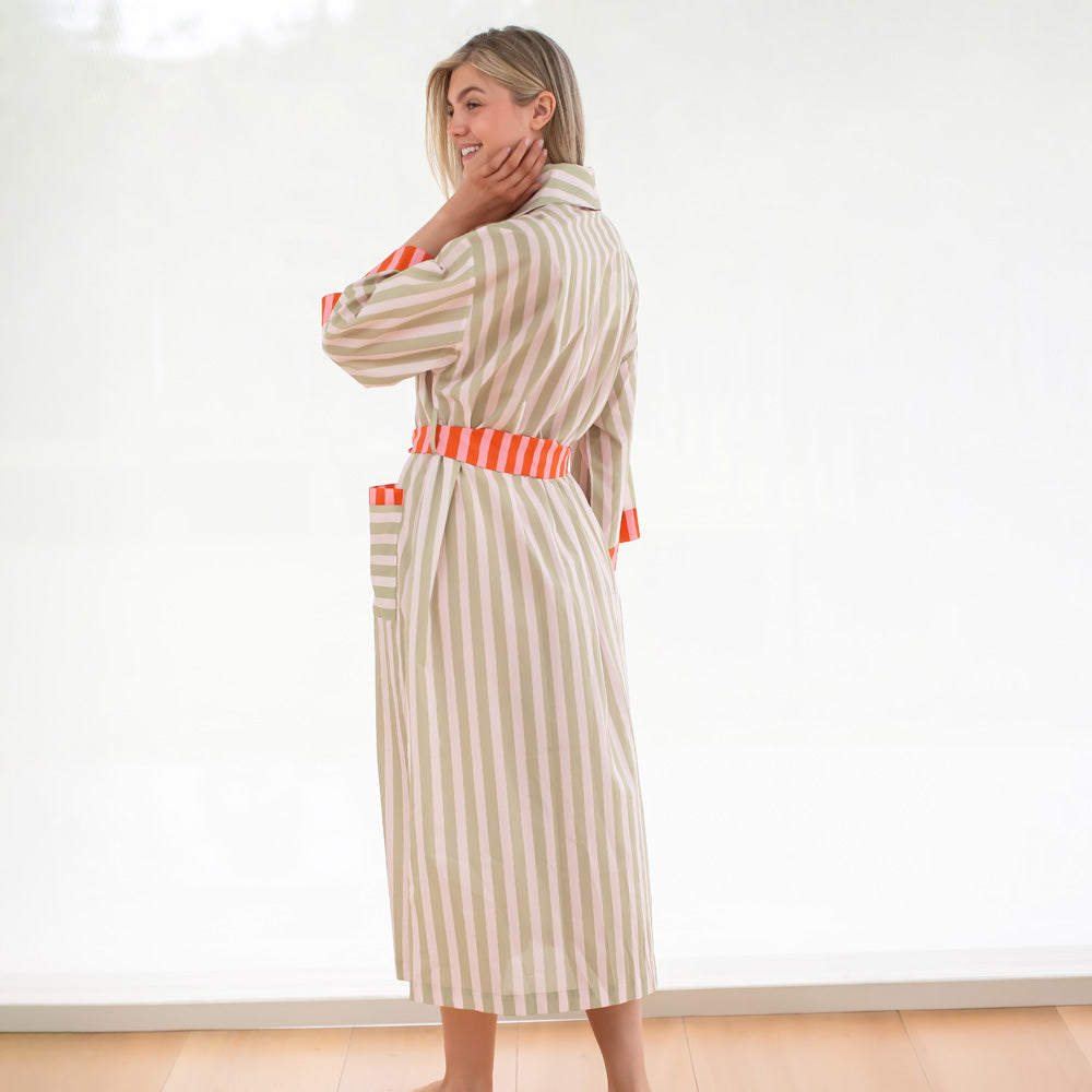 Woman wearing a striped robe with orange accents in a minimal indoor setting