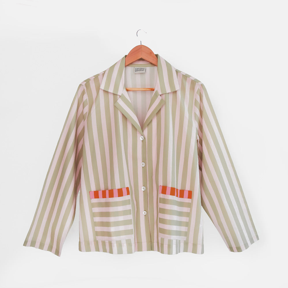 Striped pyjama shirt with red accents on a hanger against a white background
