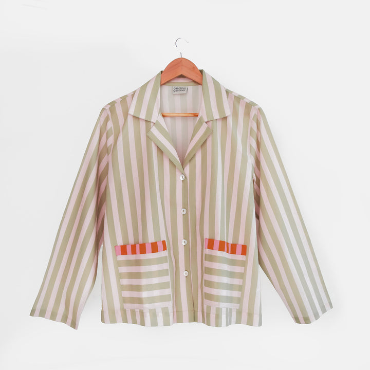 Striped pyjama shirt with red accents on a hanger against a white background