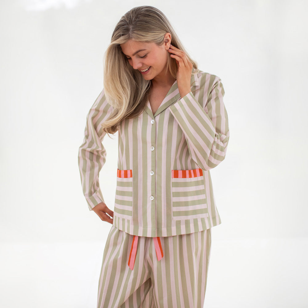Woman wearing a green and beige striped pajama set on a white background