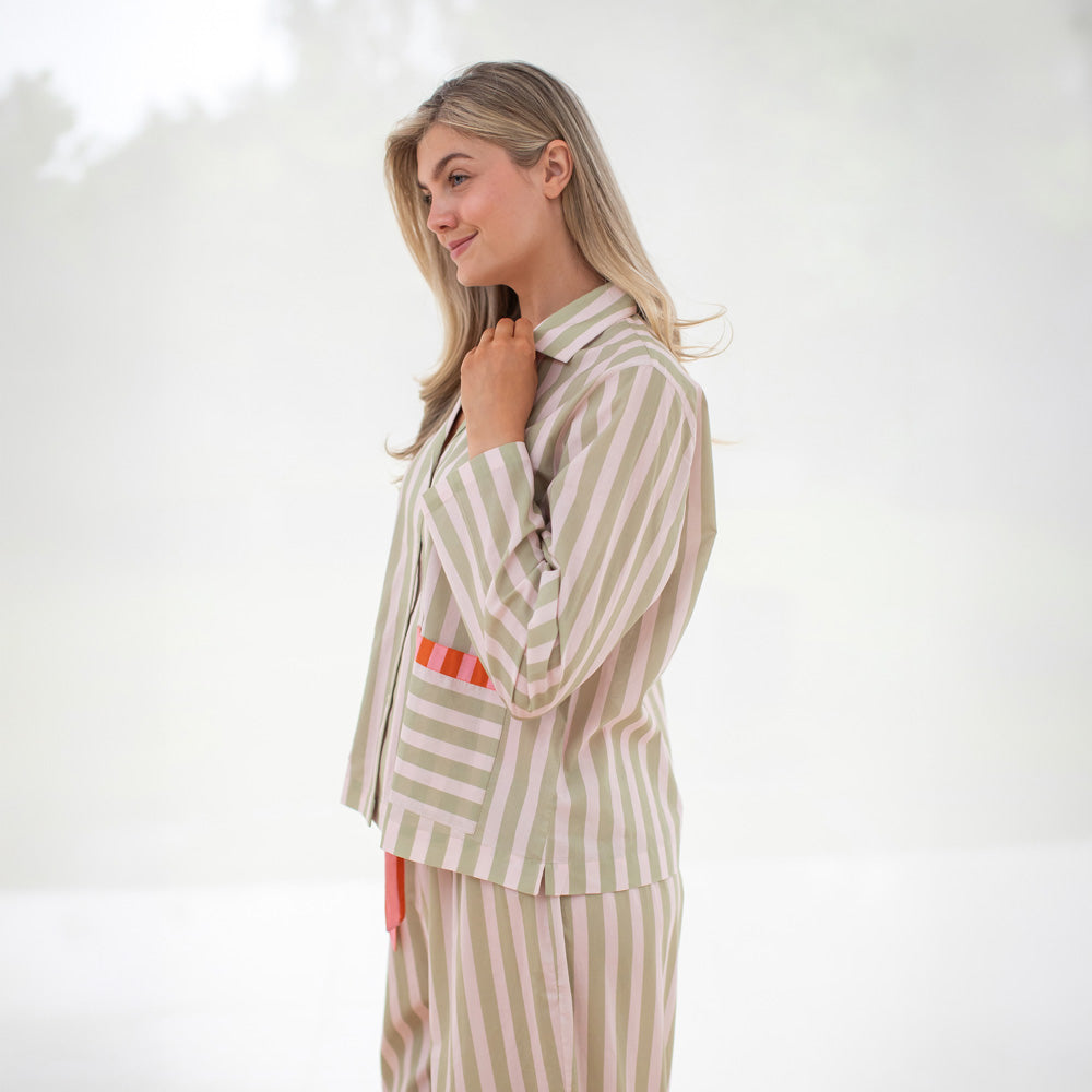 Woman wearing a beige and white striped pyjama set on a white background