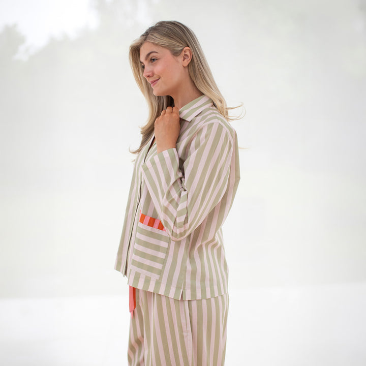 Woman wearing a beige and white striped pyjama set on a white background