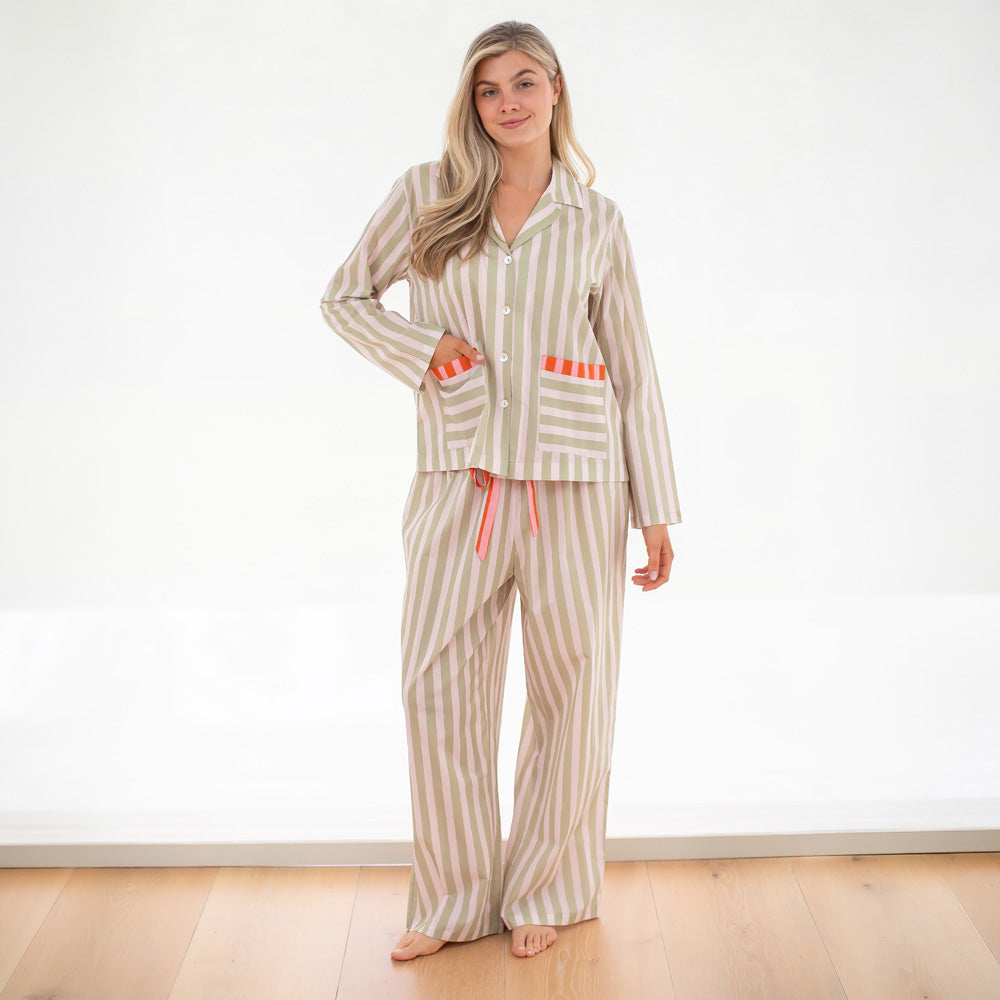 Woman wearing a striped pajama set with pink accents on a white background