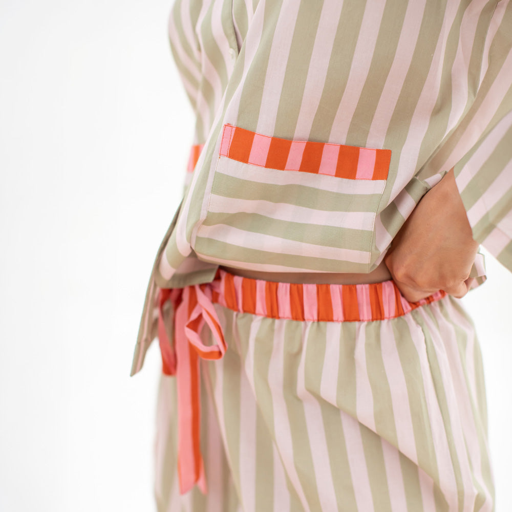 Woman wearing a striped pajama set with pink accents on a white background