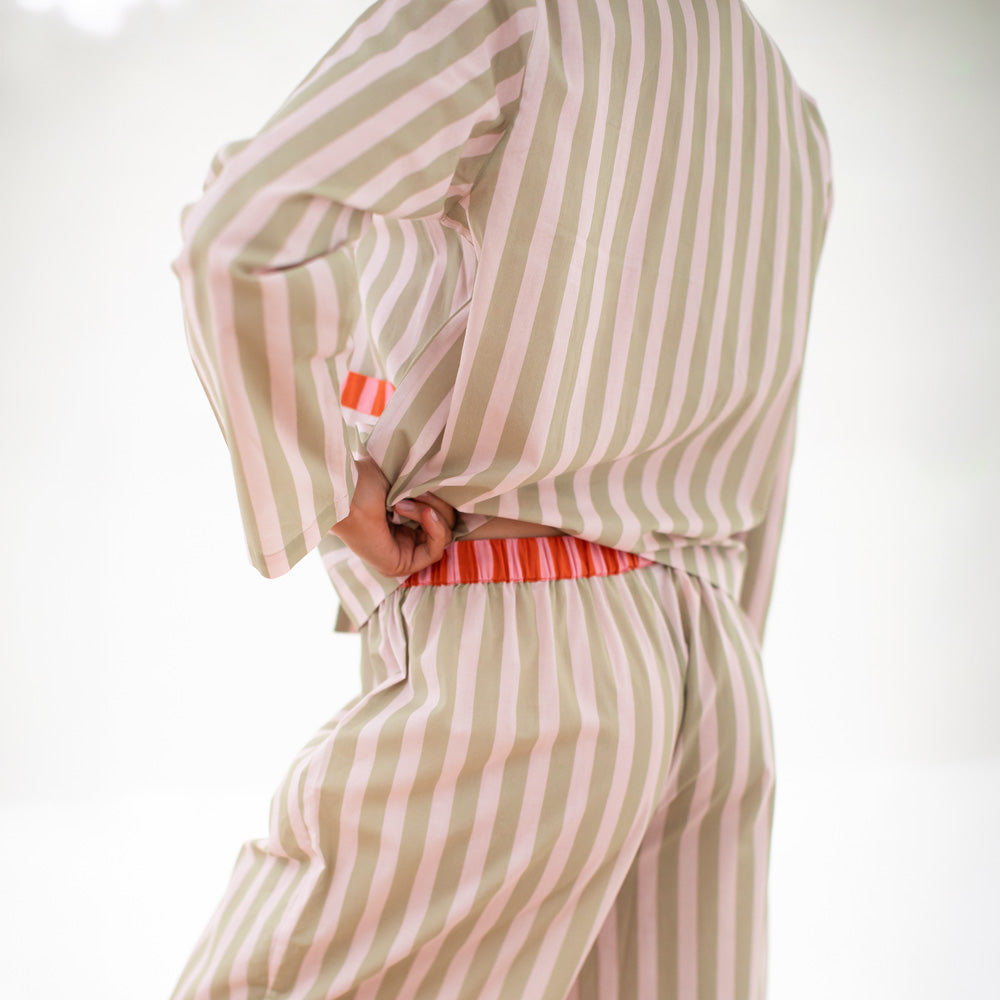 Woman wearing a striped pajama set with pink accents on a white background