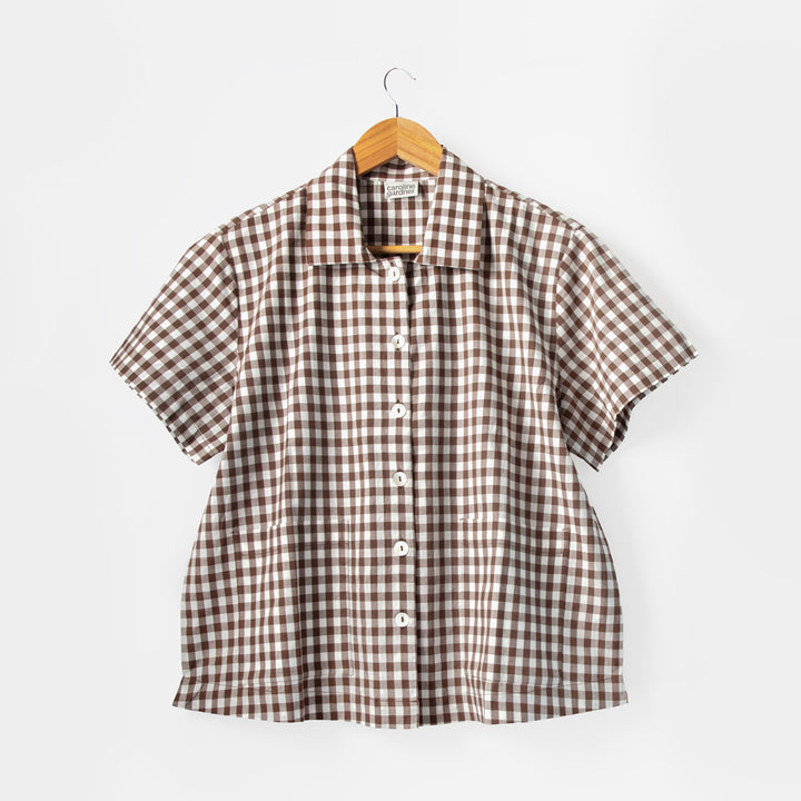 Brown and white checkered shirt on a hanger against a white background