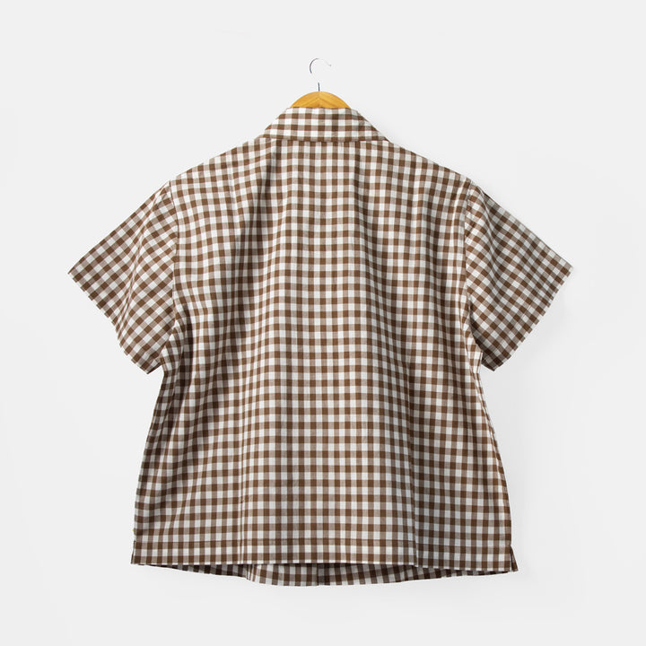 Brown and white checkered shirt on a hanger against a white background