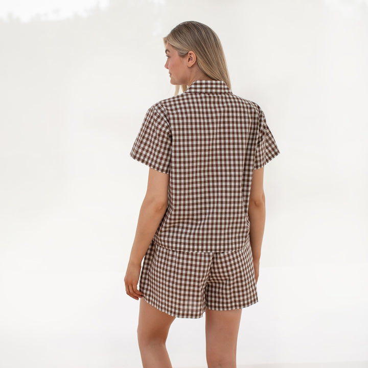 Woman wearing a brown and white checkered romper on a white background