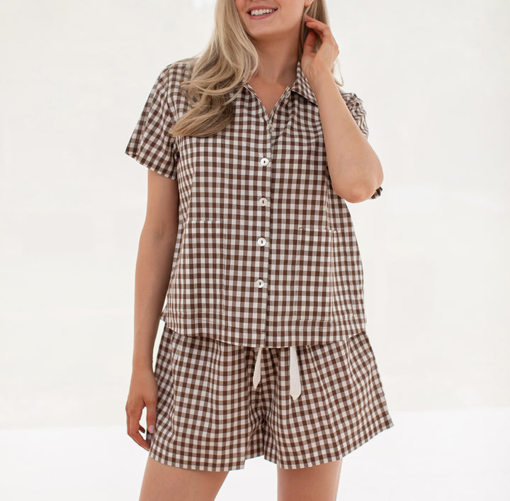 Woman wearing a brown and white checkered shirt and shorts set on a white background