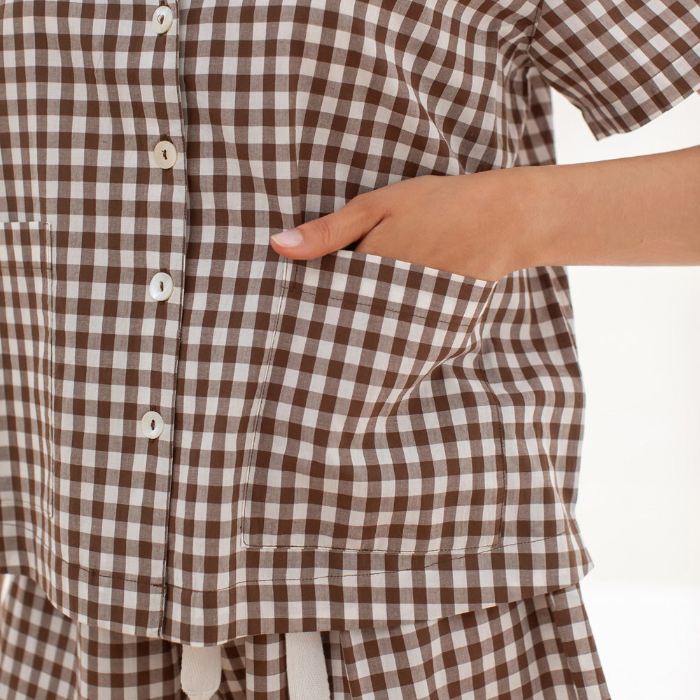 Brown and white checkered shirt with a hand in the pocket on a white background