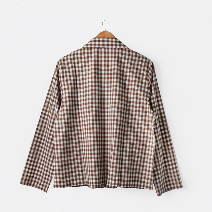Brown and white checkered shirt on a hanger against a white background