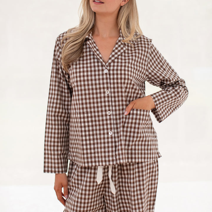 Woman wearing brown and white checkered pajamas on a white background