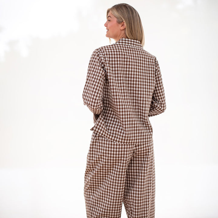 Woman wearing a brown and white checkered pyjama set on a white background