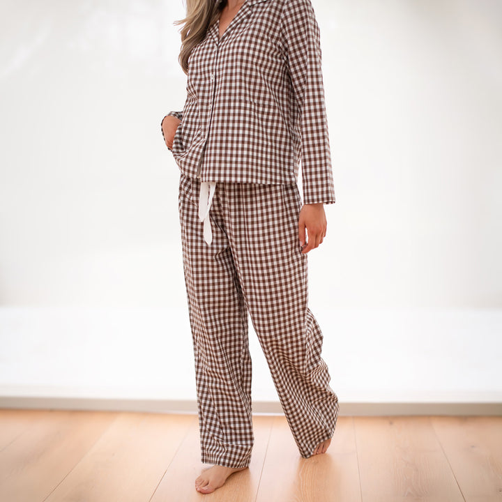 Person wearing a brown and white checkered pajama set on a plain background