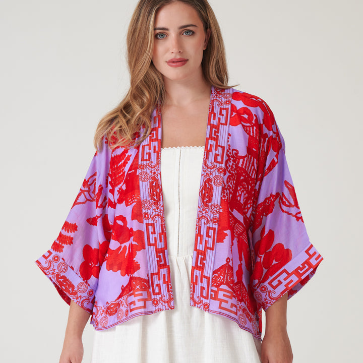 woman wearing a short kimono in japanese style design in bright red on lilac with a white dress