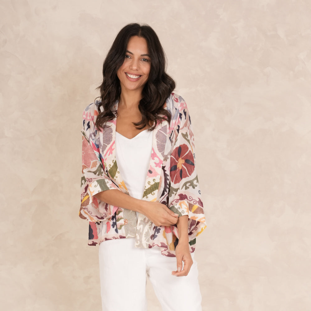 woman wearing a multi coloured patterned kimono with white trousers