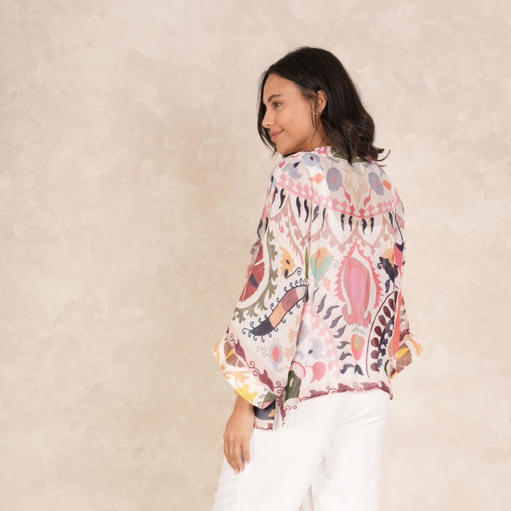 woman wearing a multi coloured patterned kimono with white trousers