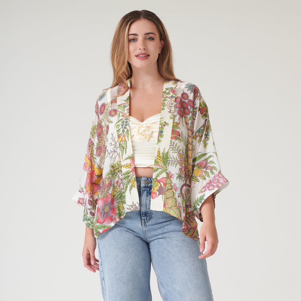 woman wearing a colourful floral print kimono with a cream camisole and light wash jeans