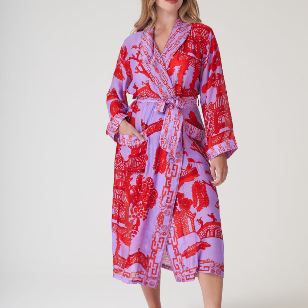 woman wearing a bright red & lilac Japanese willow print dressing gown on a light grey background