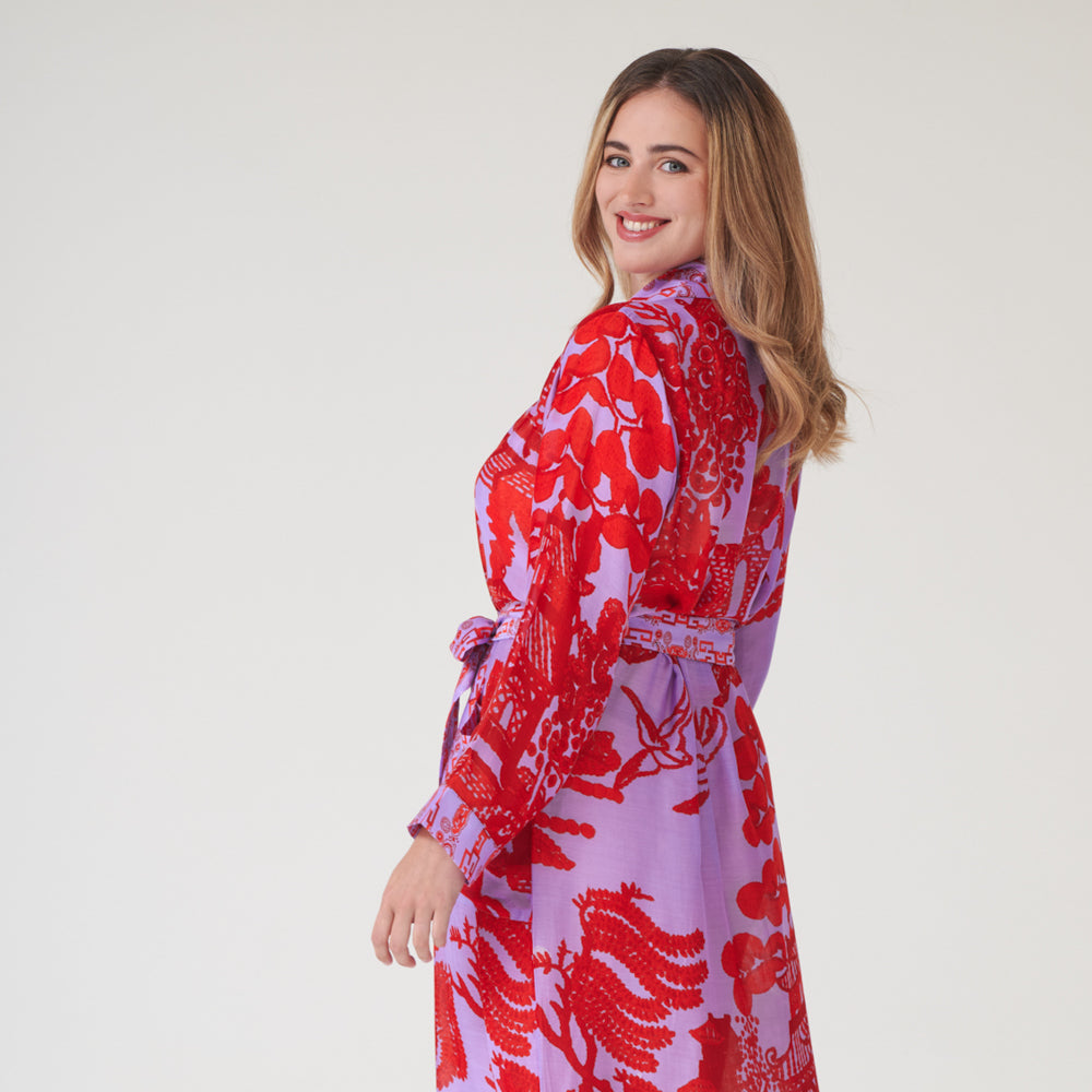woman wearing a bright red & lilac Japanese willow print dressing gown on a light grey background