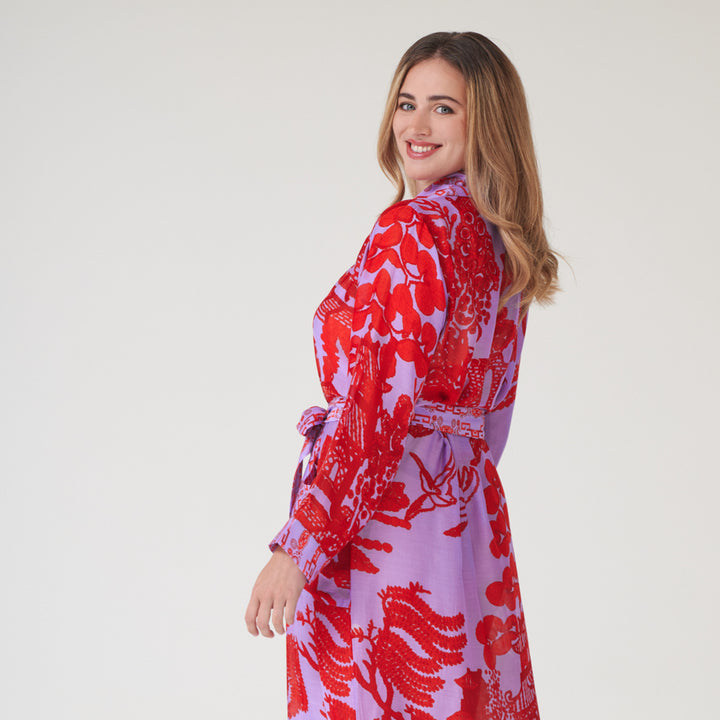 woman wearing a bright red & lilac Japanese willow print dressing gown on a light grey background