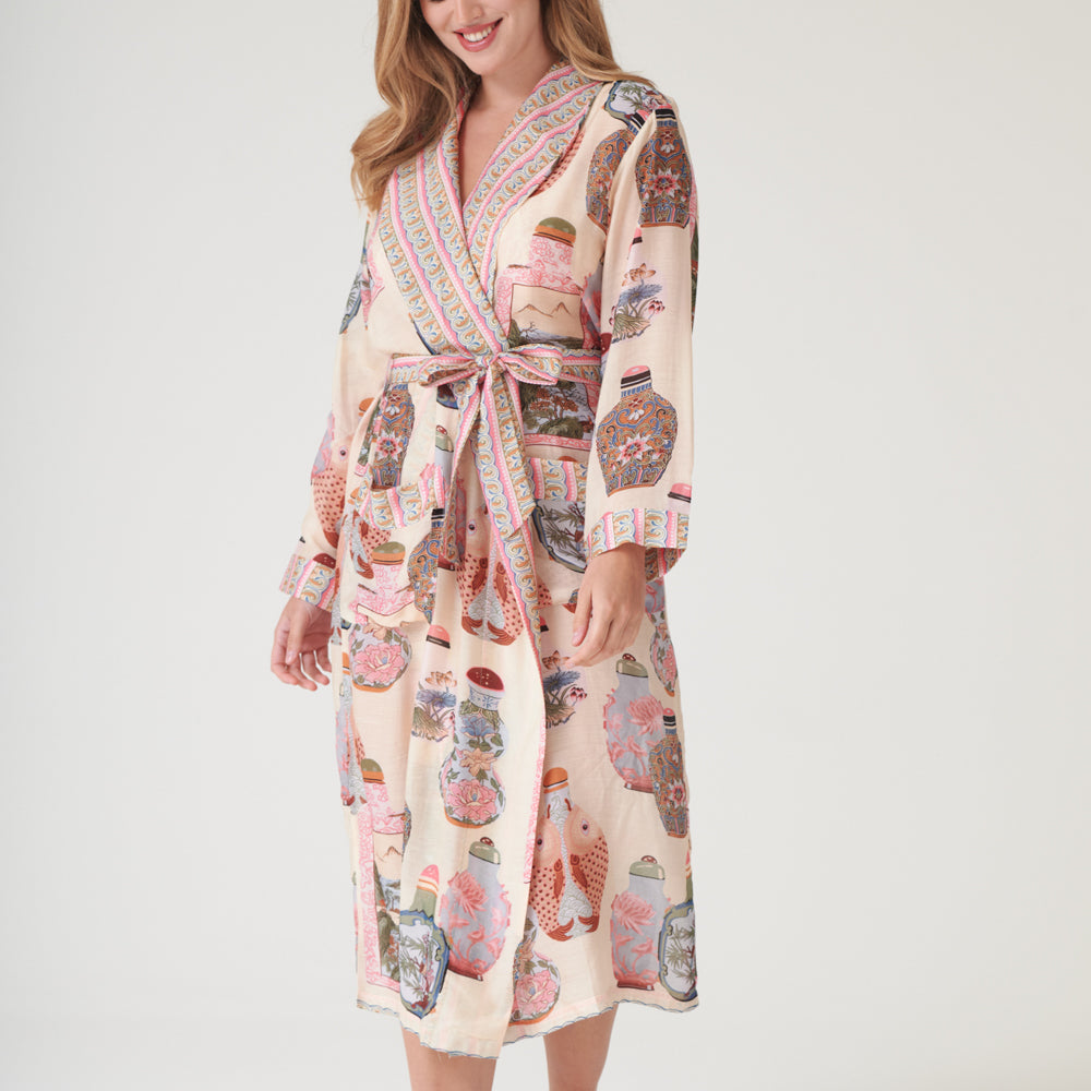 Woman wearing a perfume bottles patterned dressing gown with a neutral background