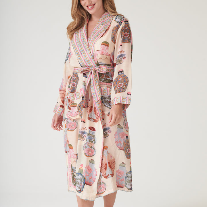 Woman wearing a perfume bottles patterned dressing gown with a neutral background
