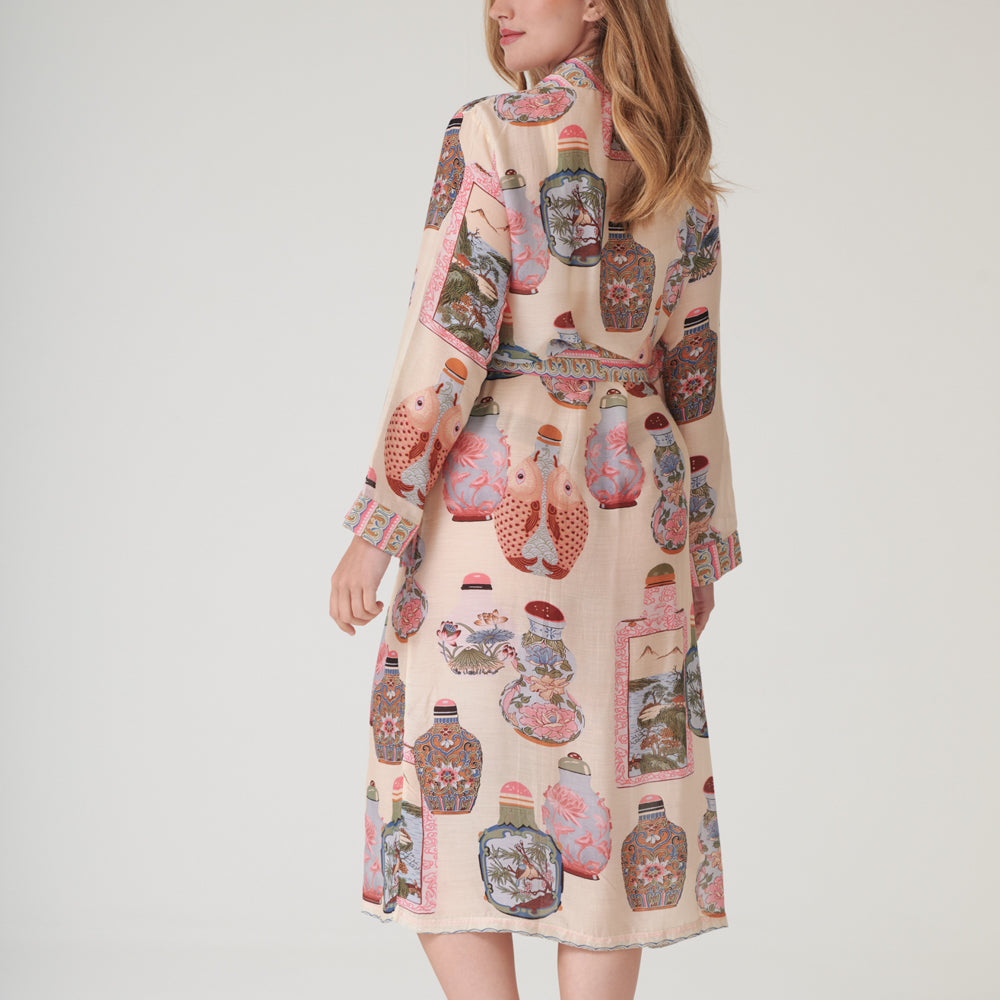 Woman wearing a perfume bottles patterned dressing gown with a neutral background