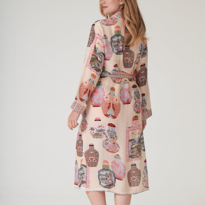 Woman wearing a perfume bottles patterned dressing gown with a neutral background