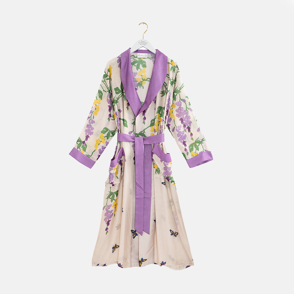 dressing gown with lilac & yellow wisteria print on a stone background with lilac trim at neck, cuff, pockets and waist tie