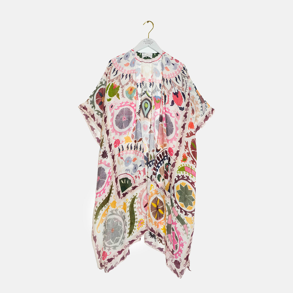 Colorful patterned throwover on a hanger against a white background