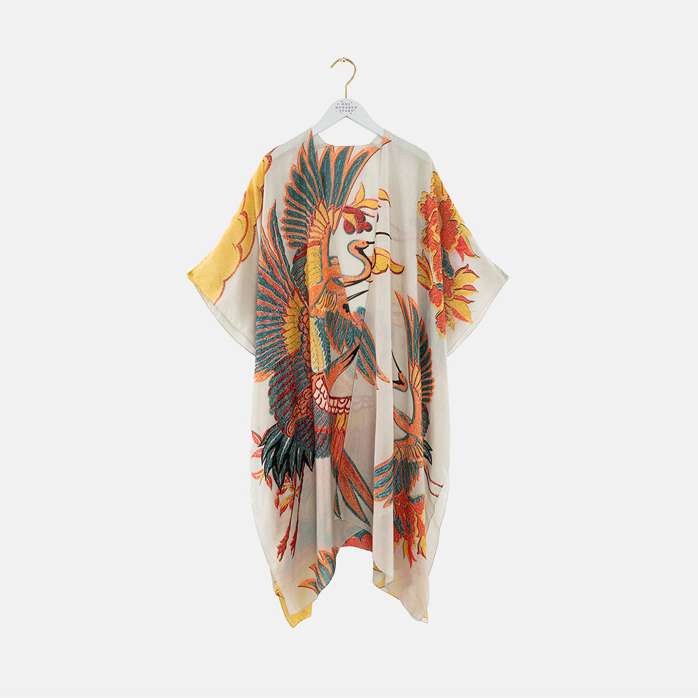 Colourful throwover with bird design on a hanger against a white background