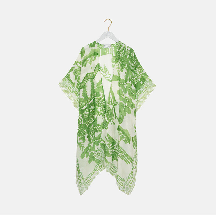 Green and white patterned throwover on a hanger against a white background
