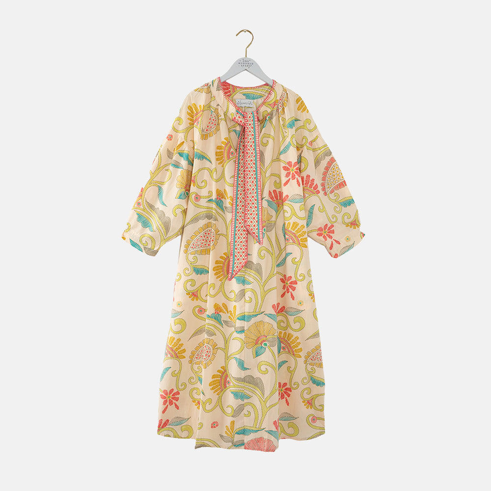 Colourful floral patterned dress on a hanger against a white background