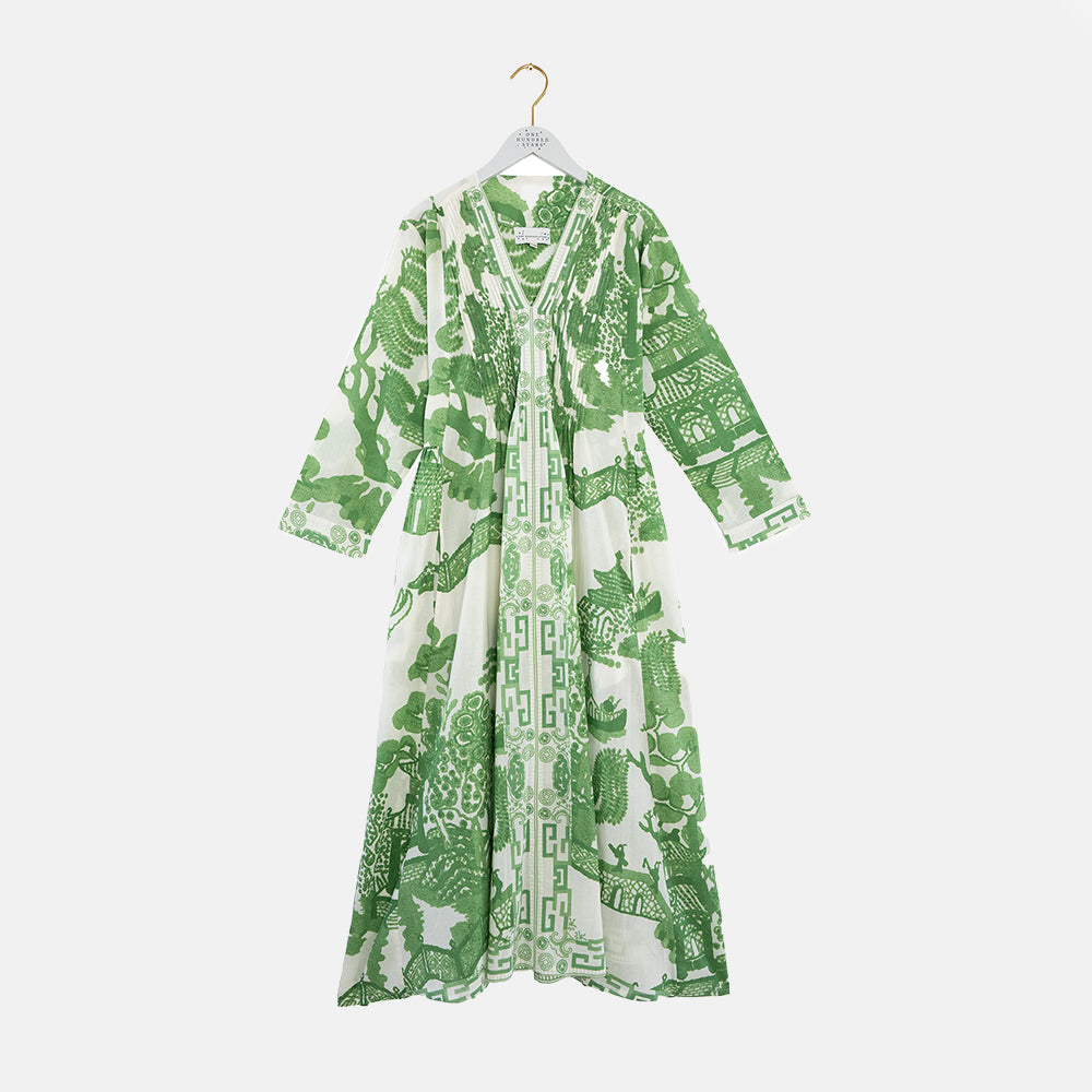 Green and white Japanese patterned dress on a hanger against a white background
