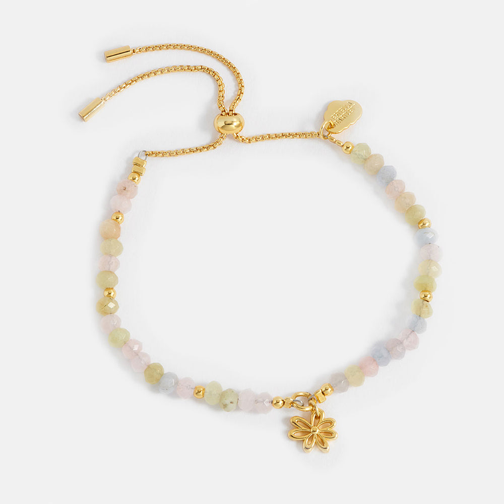 Gold bracelet with beaded chain and flower charm on a white background