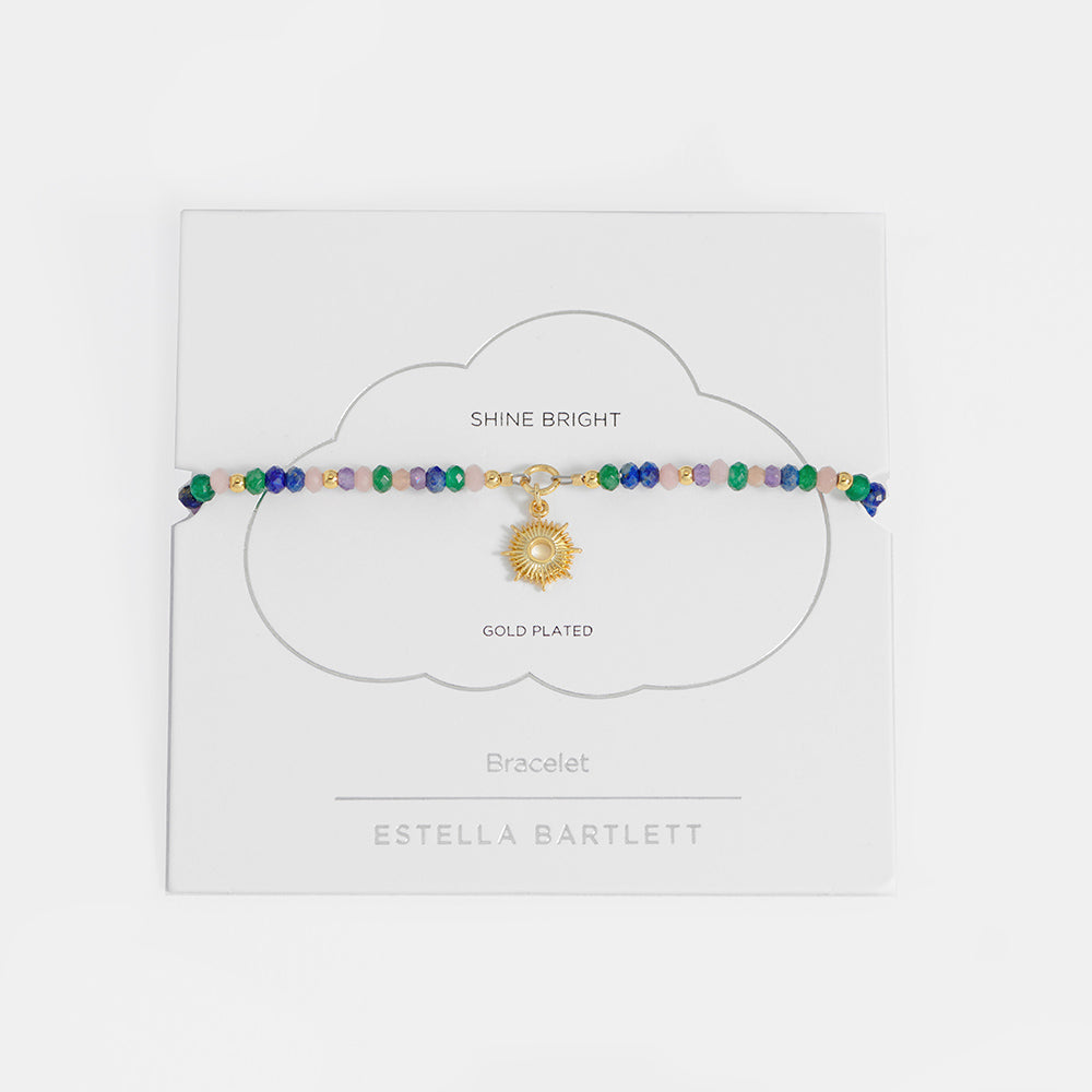 Multicolored beaded bracelet with a gold charm on a white card, branded 'Estella Bartlett'.