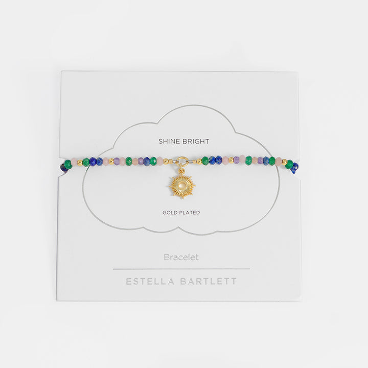 Multicolored beaded bracelet with a gold charm on a white card, branded 'Estella Bartlett'.